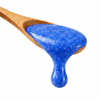 Holzlöffel mit blauem Spirulina-Honig von Algenmarkt vor weißem Hintergrund
